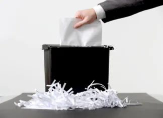 Vsi uničevalci dokumentov niso pravi Hand of businessman putting a document in paper shredder
