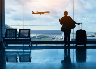 5 razlogov zakaj je letenje vse bolj nevarno travel by plane, woman passenger waiting in airport, silhouette of passenger in airport watching aircraft taking off