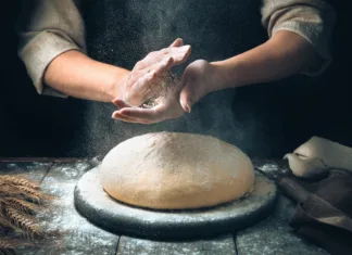 Skrivnosti priprave domačega testa za pico Women's hands knead the dough, from which they will then make bread, or pizza. A cloud of flour flies around like dust.