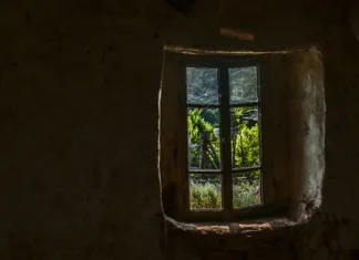 Pozabljeno mesto duhov v Bolgariji – tako pozabljeno, da je brez imena Wooden window of old abandoned neglected country house with view from inside