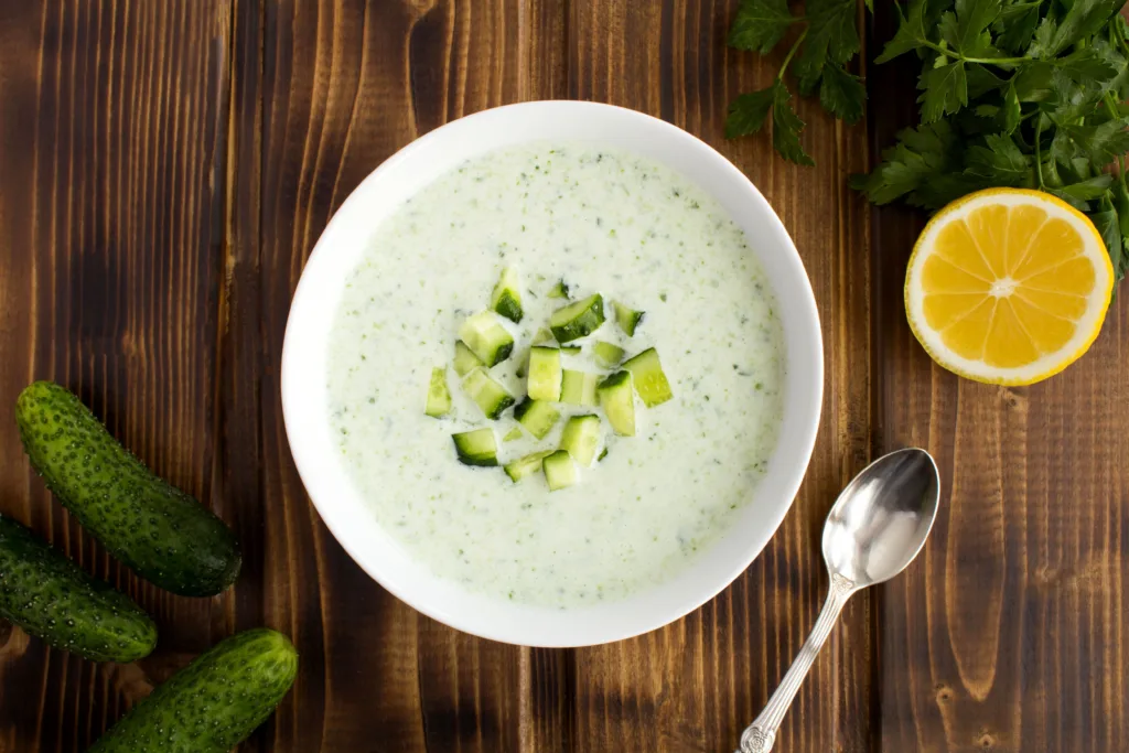 Yogurt smoothies with cucumber in the white bowl on the brown wooden background.Top view. Close-up.