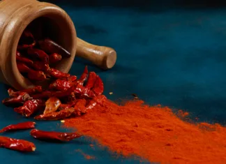 Vodič po začimbah: čili Chilli Peppers and Powder with Mortar and Pestle on a blue stone background