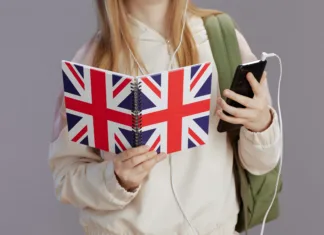 Kako uspešne so aplikacije za učenje jezikov? Closeup on girl with backpack, english flag workbook, headphones and smartphone against grey.