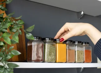 Vodič po začimbah za začetnike: Vse pomembne informacije o uporabi začimb Cropped hand holding jar of spices on kitchen.