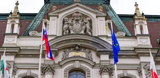 Facade of university building at the old town of City of Ljubljana with flags on a cloudy summer day. Photo taken August 9th, 2023, Ljubljana, Slovenia.