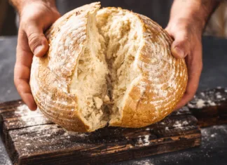 Kaj moraš vedeti o peki domačega kruha? Male baker breaks freshly baked loaf of bread