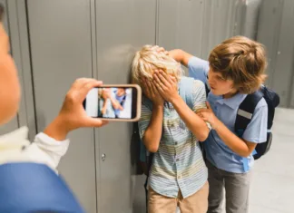 Nasilnega učenca so prešolali, bo šola rabila varnostnika? Schoolchildren cruel boys filming on the phone torturing bullying their classmate in school hall. Puberty difficult age