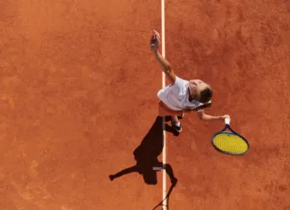 Je tenis res najbolj zdrav šport na svetu? Top view of a professional female tennis player serves the tennis ball on the court with precision and power.