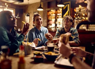 Ideje za prijetno druženje ob hrani Young happy woman and her friends talking while eating in a pub.