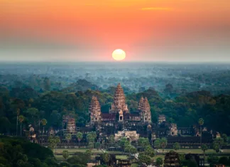 Ali poznaš največji tempelj na svetu? A bird's eye view of the Angkor Wat temple surrounded by greenery at sunset in Cambodia
