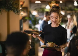 Koliko ur na mesec lahko dela študent? A waitress serving customers food at a restaurant in Newcastle-Upon-Tyne.