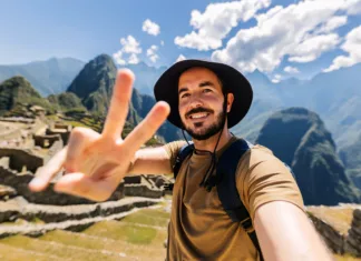 Kako potovati po svetu, ne da bi zapravil veliko? Happy young man taking selfie portrait at Macchu Picchu in Peru. Adventurer male enjoying vacation in South America.