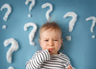 Katere sposobnosti dojenčkov so ključne za njihov kognitivni razvoj? little boy lying on blue blanket with lots of question marks