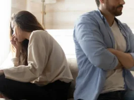 Stressed young married couple sitting separately on different sides of sofa, ignoring each other after quarrel. Offended spouses do not talk communicate, feeling depressed disappointed after argue.