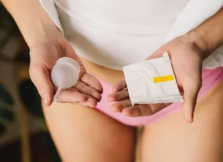Vlada postavlja zgled: brezplačni menstrualni higienski pripomočki Woman holding two alternatives of hygiene products for females holding feminine hygiene pad and menstrual cup. Women's health and alternative hygiene. Zero waste alternatives