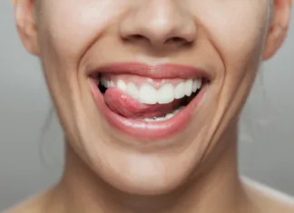 Naučite se popolne tehnike ščetkanja zob A close-up image capturing a happy woman licking her lips, showcasing healthy teeth and expressing joy and satisfaction. Perfect for dental hygiene promotions.