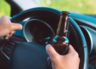 Poostren nadzor: Začetek akcije Slovenija piha 0,0 Closeup of drunk driver hands on the steering wheel with a bottle of beer. Driving under alcohol influence. High quality photo