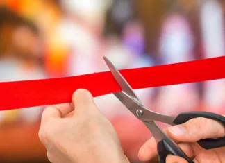 Nova veriga trgovin v Sloveniji, prvo odprli v Trbovljah Hand with scissors cutting red ribbon - opening ceremony concept