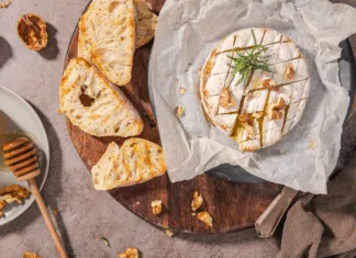 Pečeni sir camembert bo skriti adut priprave hrane v zaključku leta Brie type of cheese. Camembert cheese. Fresh sliced Brie cheese on a wooden tray with nuts, honey and leaves. Italian, French cheese.