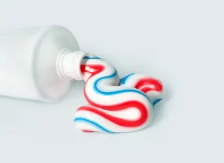 Ali res potrebujemo zobno pasto za ustno nego? Dental hygiene product. Tricolor toothpaste, copy space. White tube with toothpaste isolated on light background