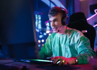 Znanost odgovarja: Zakaj se mladi hitro zasvojijo z videoigrami? Gaming at Home: Portrait of a Gamer Wearing Headphones and Playing Online Game on Personal Computer. Professional Stylish Male Player Enjoying Online Multiplayer PvP Tournament.