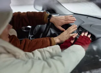 Je pametno takoj prižgati gretje, ko se usedemo v avto? Hands of young couple in winterwear sitting in front of stove inside car during travel and keeping their hands against warm air
