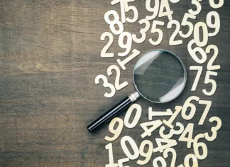 Kaj so naravna števila? Magnifying glass in scattered numbers on wood background, calculation, mathematics concept