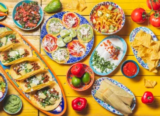 Slavna mehiška restavracija v centru Ljubljane se poslavlja: Kaj jo bo nadomestilo? Mexican festive food for independence day - independencia chiles en nogada, tacos al pastor, chalupas pozole, tamales, chicken with mole poblano sauce. Yellow background