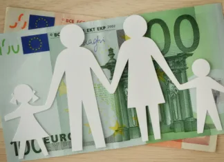 Ali se res ukinja višji otroški dodatek? Paper family cut-out on euro banknotes - Family budget concept
