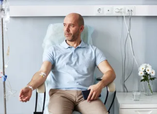 Odkrili zakaj se pri zdravljenju raka z imunoterapijo pojavijo stranski učinki Portrait of adult man sitting in comfortable chair with IV drip during treatment session in clinic