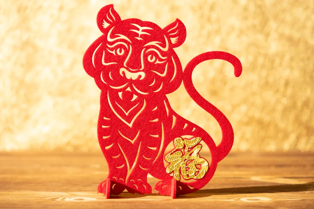 Chinese New Year of tiger 2022 mascot paper cut on a wood table in the morning the Chinese means fortune no logo no trademark