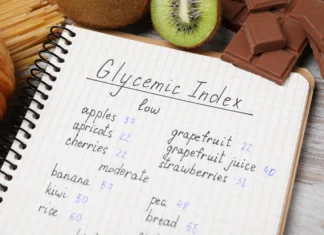 Kaj je glikemični indeks? Notebook with products of low and moderate glycemic index, kiwi and chocolate on light wooden table, closeup