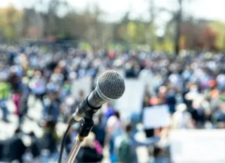 Protesti v Srbiji: »Ne bi bilo krvi, če bi bilo vse po zakonu« Protest or public demonstration, focus on microphone, blurred crowd of people in the background