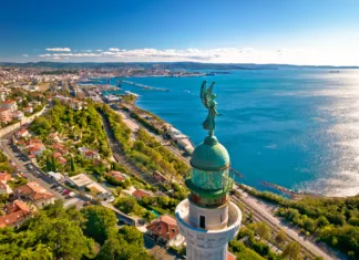 12 najočarljivejših manjših mest v Evropi Trieste lighthouse Phare de la Victoire and cityscape panoramic aerial view, Friuli Venezia Giulia region of Italy