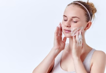 Viralna korejska kozmetika: Zakaj je tako dobra za kožo? Teenager skincare. Beautiful teenage girl with freckles and blue eyes using foaming cleanser. Face washing concept isolated on white background.