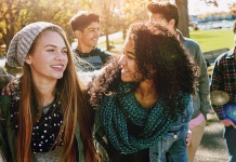 Na kaj paziti v pozni puberteti in kako si pomagati? Teenager, walking and talking with friends in park, nature or social group outdoor together with funny conversation. Happy, teen and kids laugh at joke with best friend in community or relax in fall