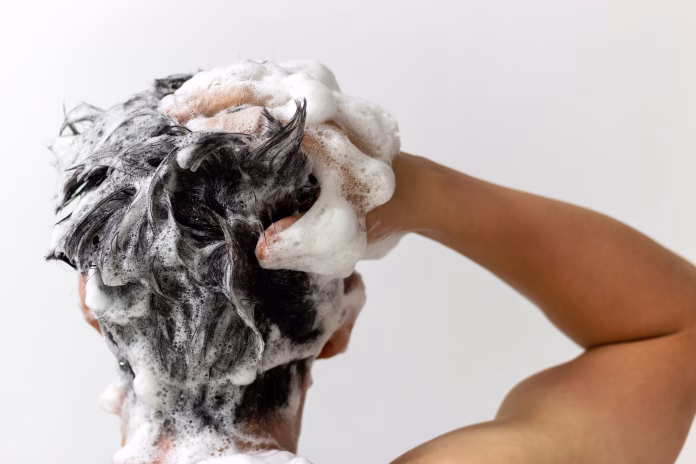 a-man-washes-his-head-with-shampoo-on-a-white-background-rear-view-stockpack-istock A man washes his head with shampoo on a white background, rear view