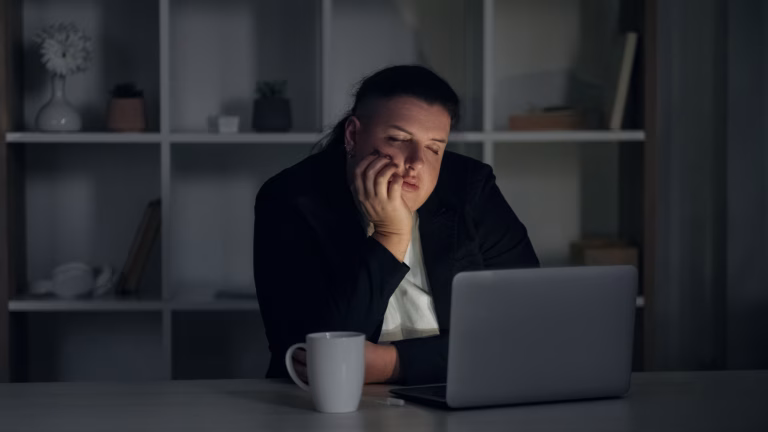 Overworked manager. Night job. Tired unhappy female employee working hard in business finishing task on deadline falling asleep at dark workplace.