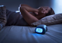 Zakaj si zjutraj uničen, čeprav si spal osem ur? Sleepless woman suffering from insomnia, sleep apnea or stress. Tired and exhausted lady. Headache or migraine. Awake in the middle of the night. Frustrated person with problem. Alarm clock with time.