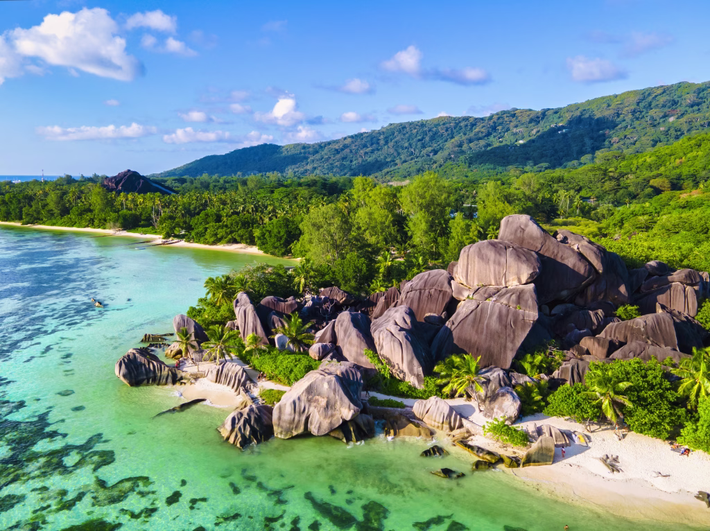 Anse Source d'Argent beach, La Digue Island, Seyshelles, Drone aerial view of La Digue Seychelles bird eye view.of tropical Island, couple men and woman walking at the beach during sunset at a luxury vacation