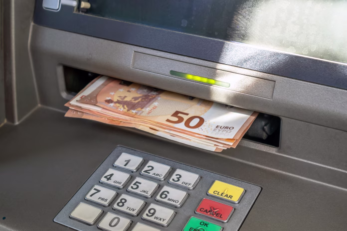 ATM and cash money. Euros withdrawal from an ATM machine, closeup view