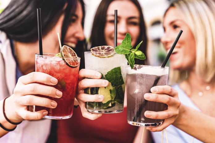 group-of-happy-friends-toasting-and-drinking-fancy-cocktails-at-bar-terrace-three-young-girls-drink-mojito-and-clinking-glass-together-at-pub-enjoying-happy-hour-at-summer-party-life-style-concept-stockpack-istock Group of happy friends toasting and drinking fancy cocktails at bar terrace-Three Young girls drink mojito and clinking glass together at pub enjoying happy hour at summer party- Life Style concept