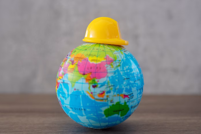 Hard hat on top of world globe. Copy space for text. Labor day, safety first concept.