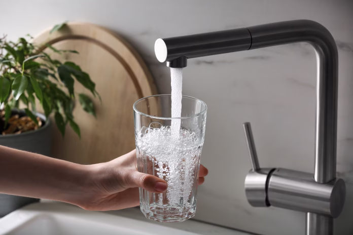 woman-filling-glass-with-tap-water-from-faucet-in-kitchen-closeup-stockpack-istock Woman filling glass with tap water from faucet in kitchen, closeup