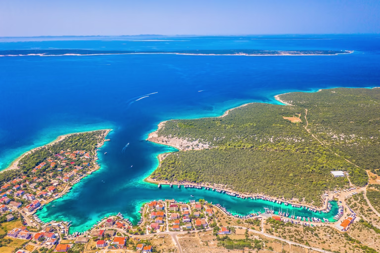 A beautiful aerial view of the small coastal village of Simuni on Pag Island, Croatia, known for its scenic bay, and popular camping tourism set among pine trees and Mediterranean nature
