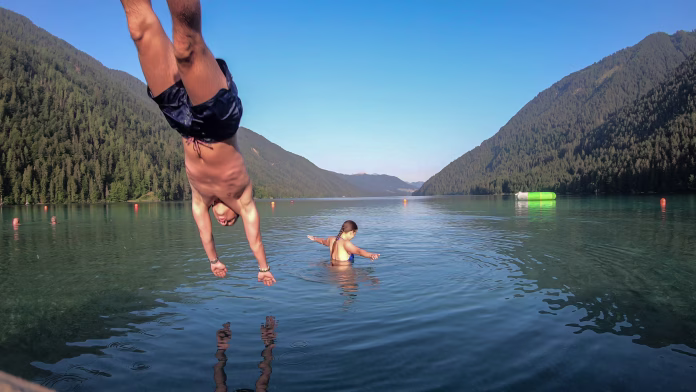 a-couple-playing-at-the-weissensee-lake-in-austrian-alps-the-man-is-jumping-into-the-water-from-the-wooden-pier-the-woman-is-splashing-the-water-around-happiness-and-relaxation-stockpack-istock A couple playing at the Weissensee lake in Austrian Alps. The man is jumping into the water from the wooden pier. The woman is splashing the water around. Happiness and relaxation