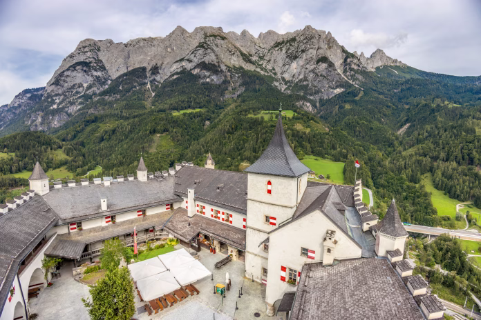 Castle Burg Hohenwerfen in Austria. Medieval architecture and culture, ancient brick walls and towers on a hill among the Alps mountains under blue sky clouds