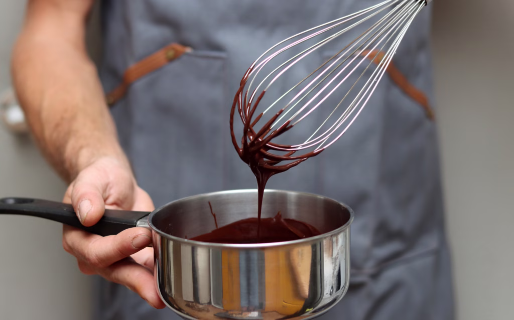 Chef making chocolate cake, closeup of hands holding a pot