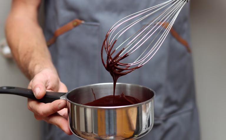 Chef making chocolate cake, closeup of hands holding a pot