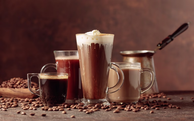 Coffee and chocolate drinks with scattered coffee beans on a brown background.
